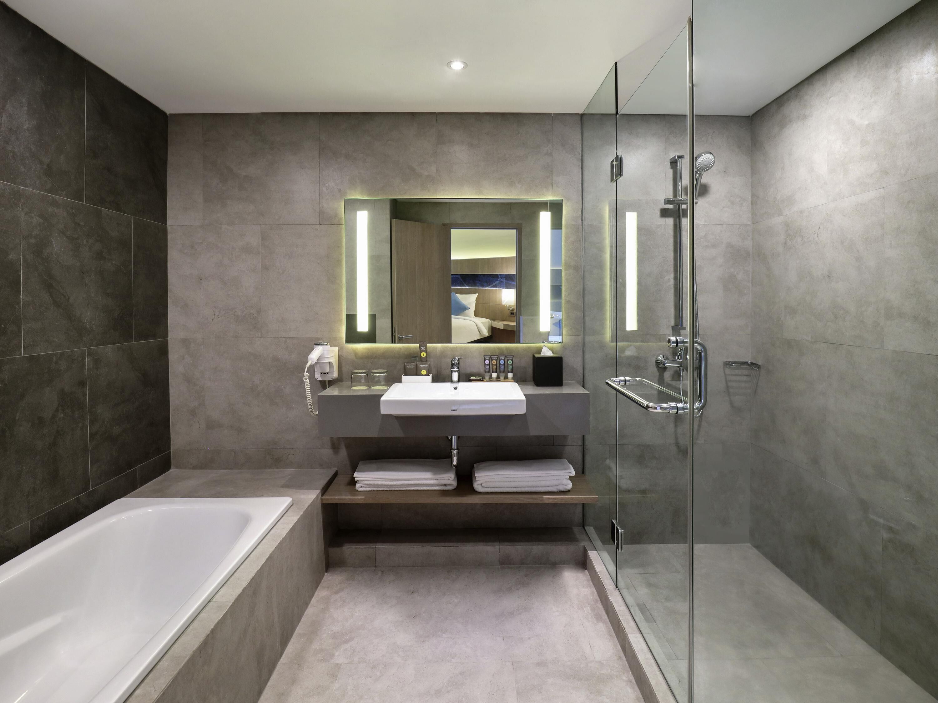 Un baño moderno con bañera, cabina de ducha de vidrio y tocador con espejo.