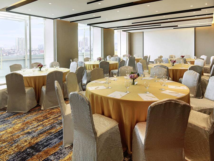 A conference room with round tables, chairs, and a carpeted floor.