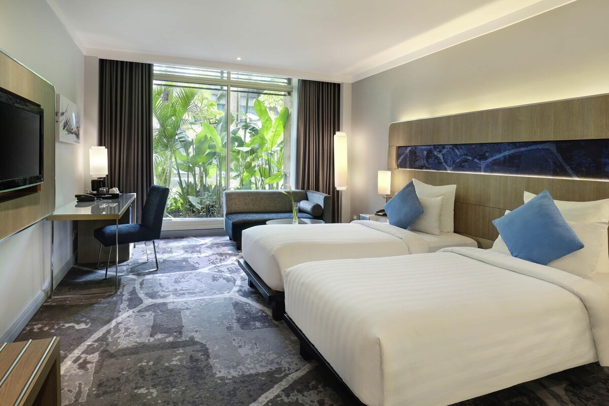 Ein Hotelzimmer mit Bett, Schreibtisch, Stuhl und Fernseher.