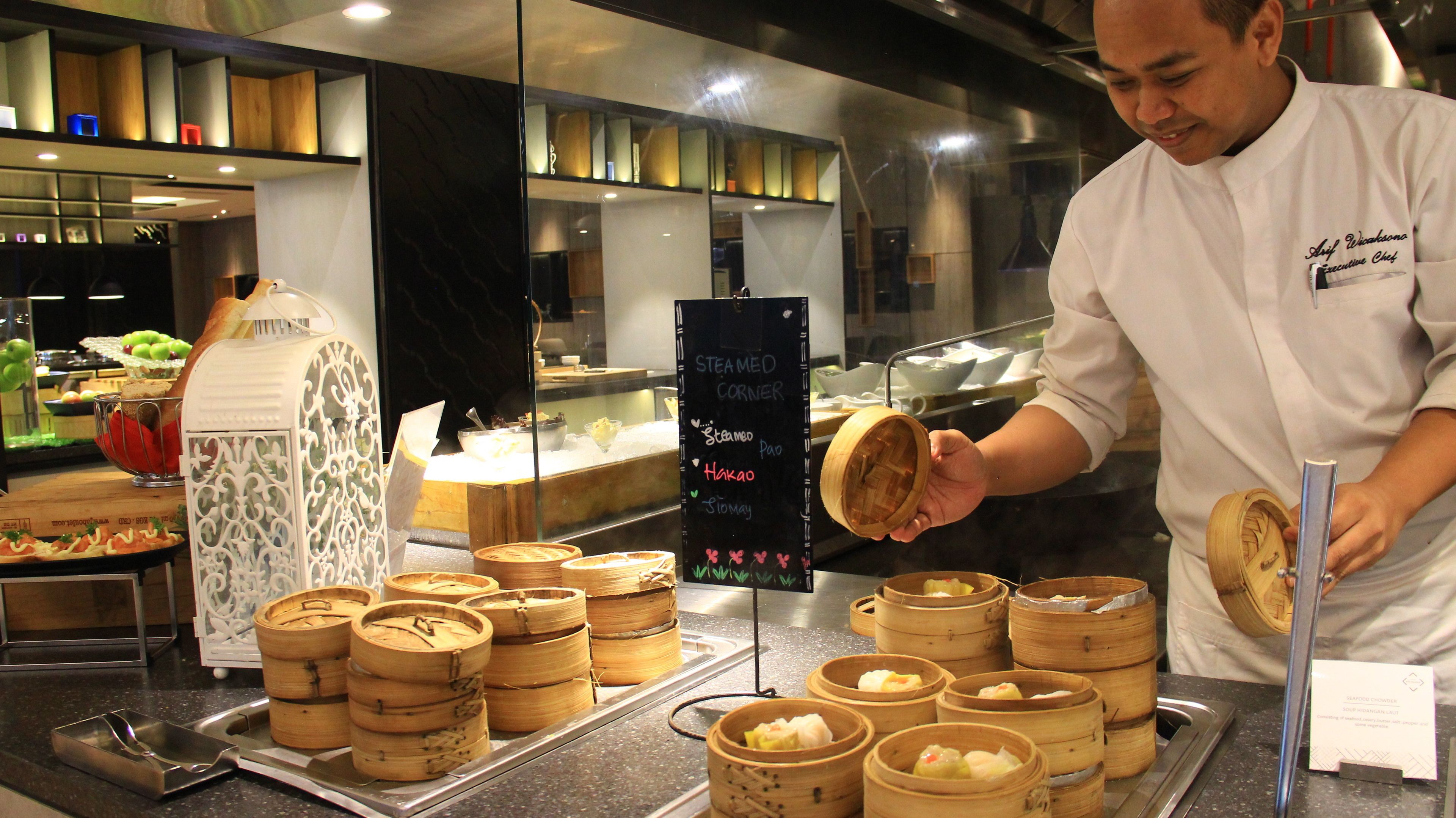 A chef preparing steamed corner dishes in a commercial kitchen.