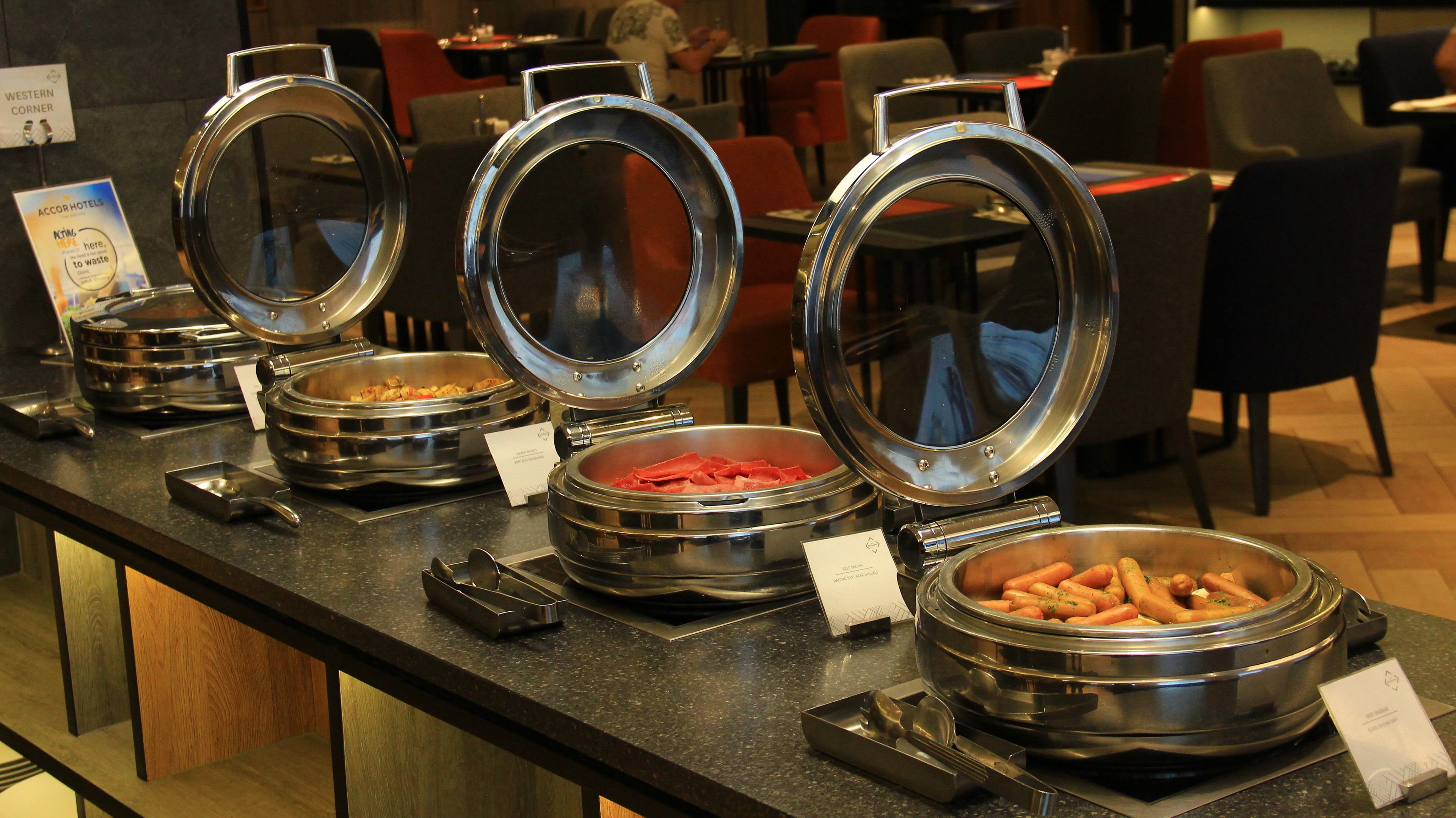 A buffet setup with multiple food stations, including a meat station and a vegetable station, in a restaurant setting.