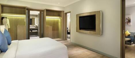 Una habitación de hotel con cama, televisor montado en la pared y vestidor.