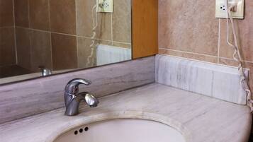 A bathroom with a marble sink, a mirror, and a hairdryer mounted on the wall.