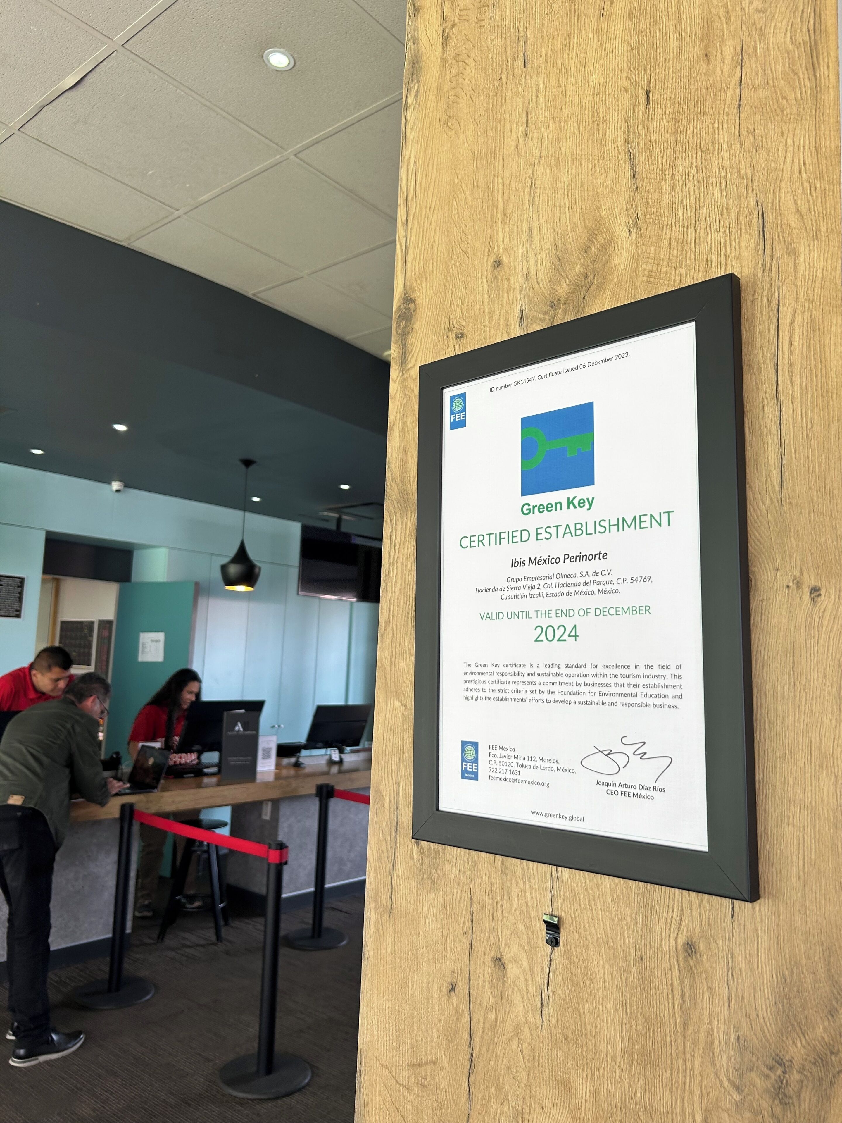 A framed Green Key Certified Establishment certificate on a wooden post.