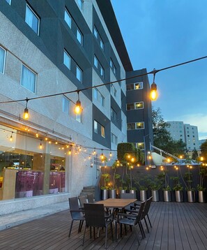 An outdoor patio with string lights, wooden tables, and chairs.