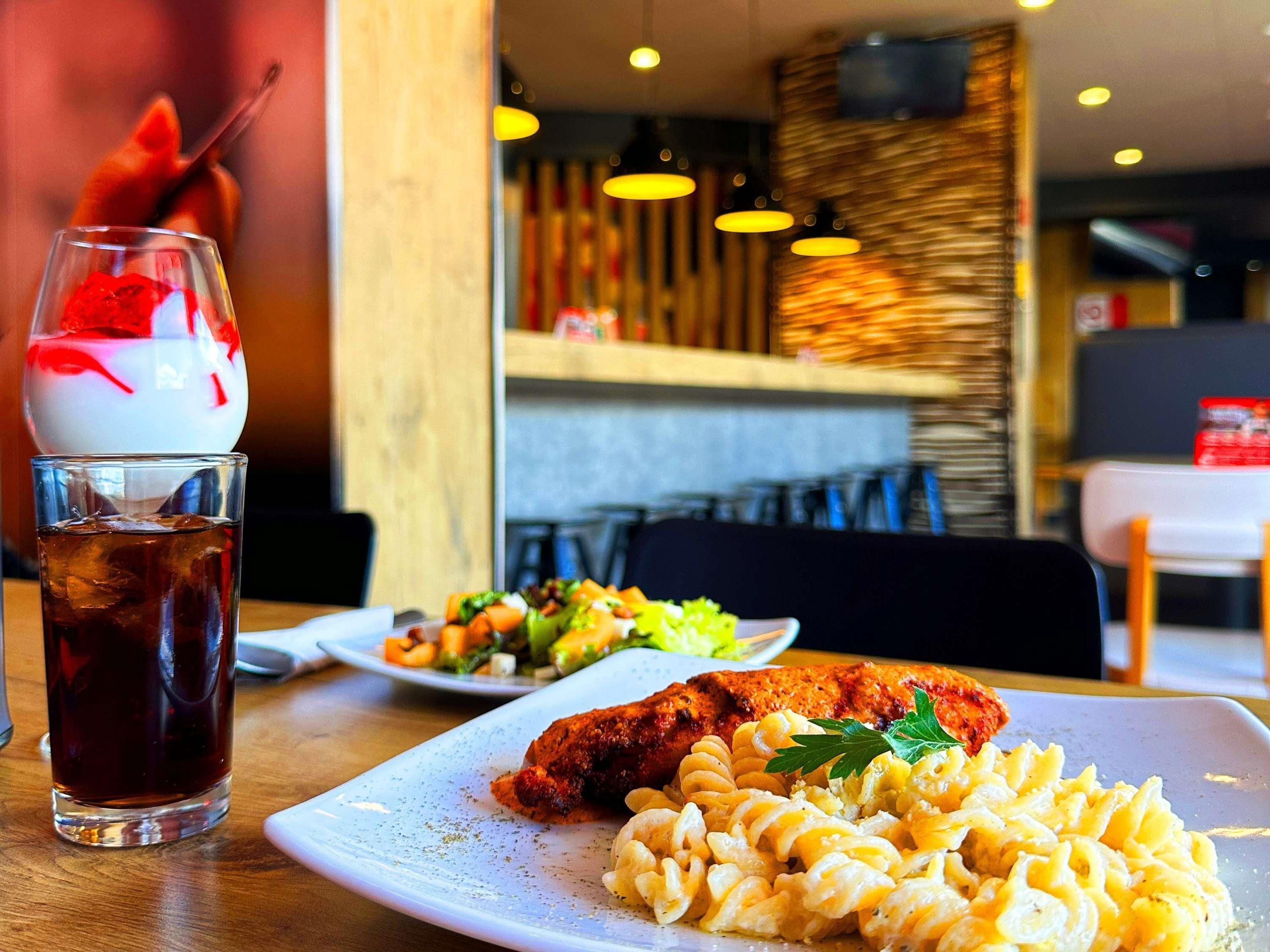A dining table with a plate of food, a glass of iced drink, and a dessert.