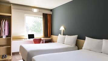 Habitación de hotel con dos camas, un escritorio con una computadora portátil, un armario y una ventana con cortinas.