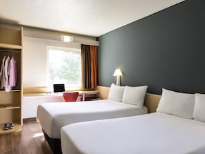 A hotel room with two beds, a desk with a laptop, a wardrobe, and a window with curtains.