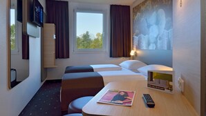 Une chambre d’hôtel avec un lit, deux tables de chevet, une télévision, un magazine et une télécommande.