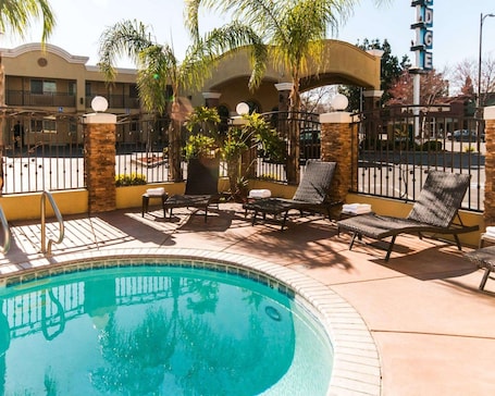 Una piscina al aire libre, sombrillas, sillones reclinables de piscina