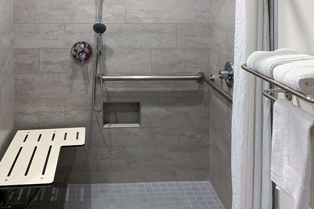 A shower area with a handheld showerhead, a grab bar, and a towel rack.