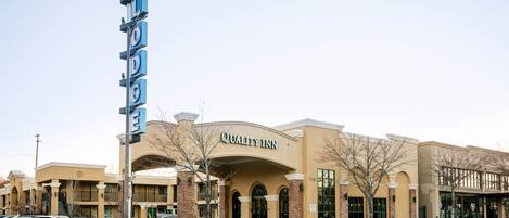 A hotel with a sign reading "Quality Inn" and a neon sign above it.