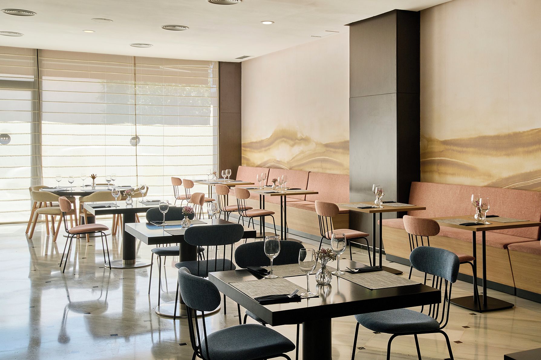 A restaurant with multiple tables and chairs, large windows, and a modern interior design.