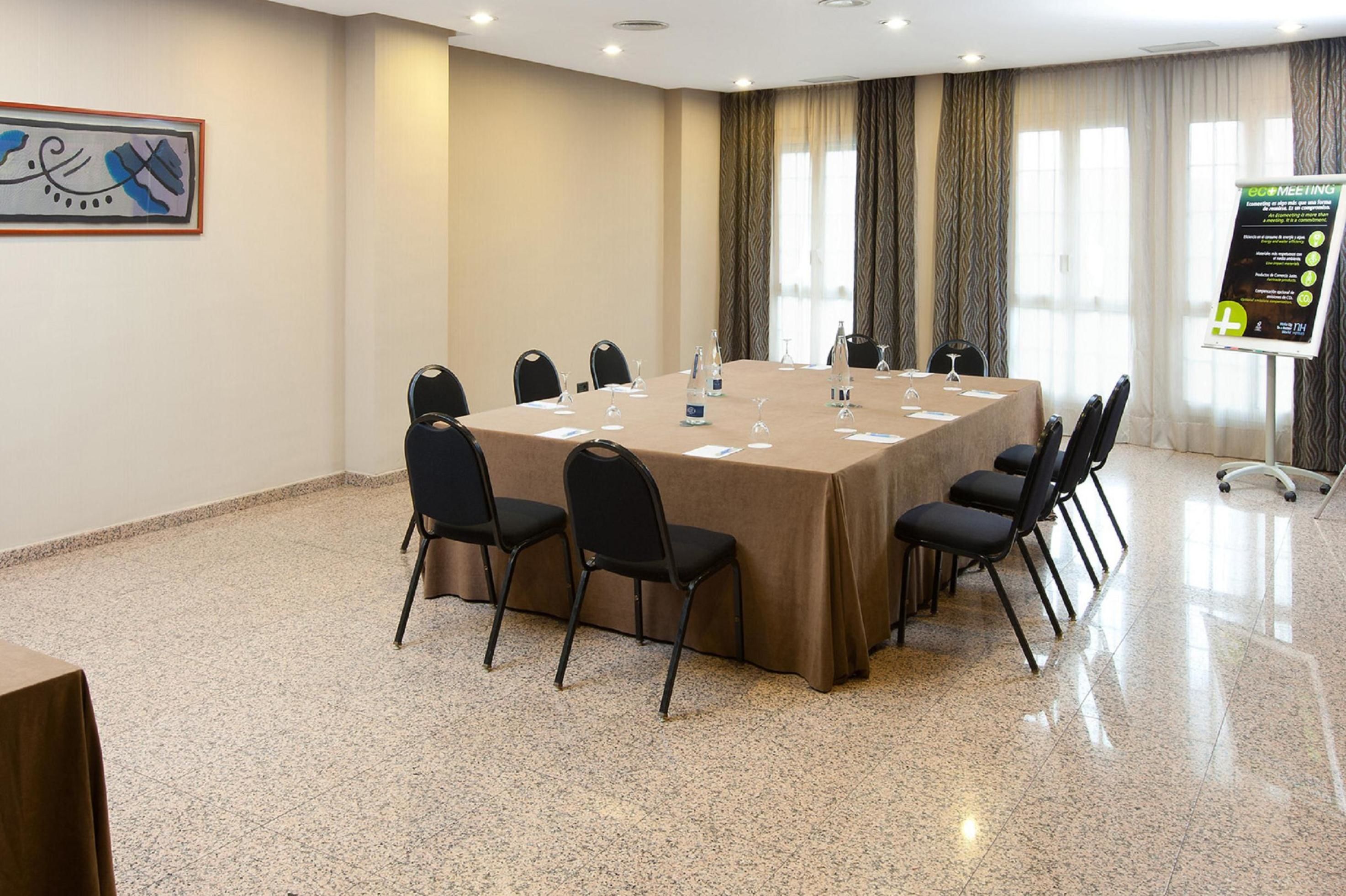 Une salle de conférence équipée d’une grande table, de chaises et d’un tableau mobile.