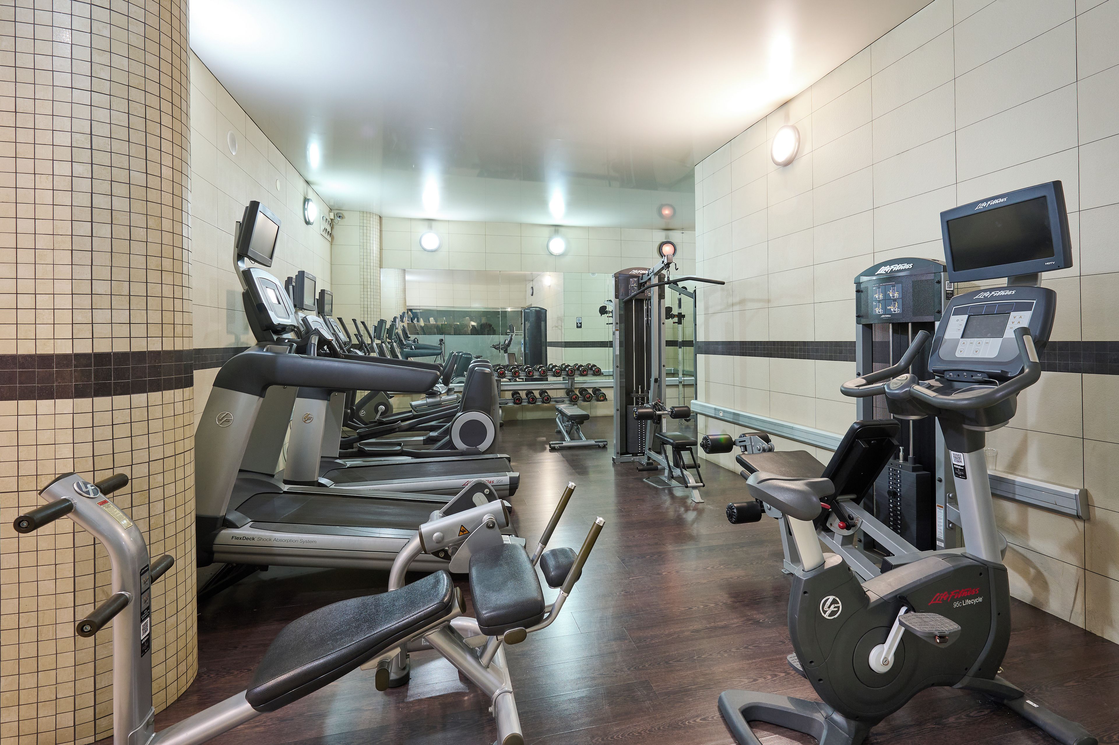 Una palestra con diverse attrezzature per esercizi, tra cui tapis roulant, macchinari per pesi e un vogatore.