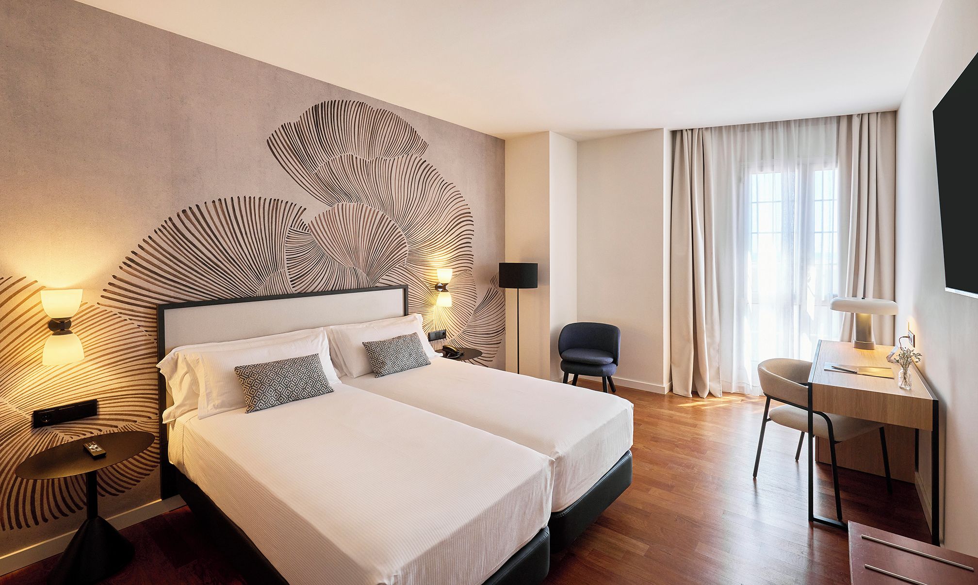 A hotel room with a large bed, two bedside tables, a desk, and a chair.