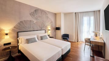 A hotel room with a large bed, two bedside tables, a desk, and a chair.