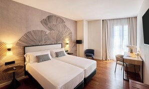 Une chambre d’hôtel avec un grand lit, deux tables de chevet, un bureau et une chaise.