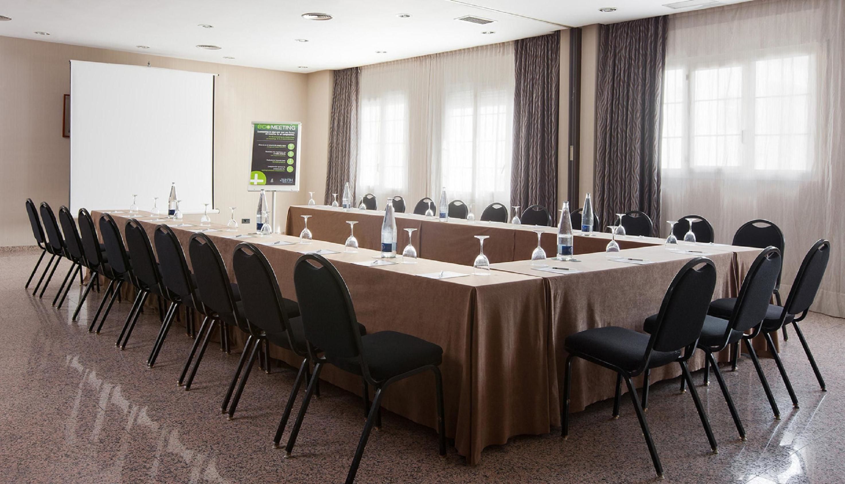A conference room with a long table, chairs, and a whiteboard.