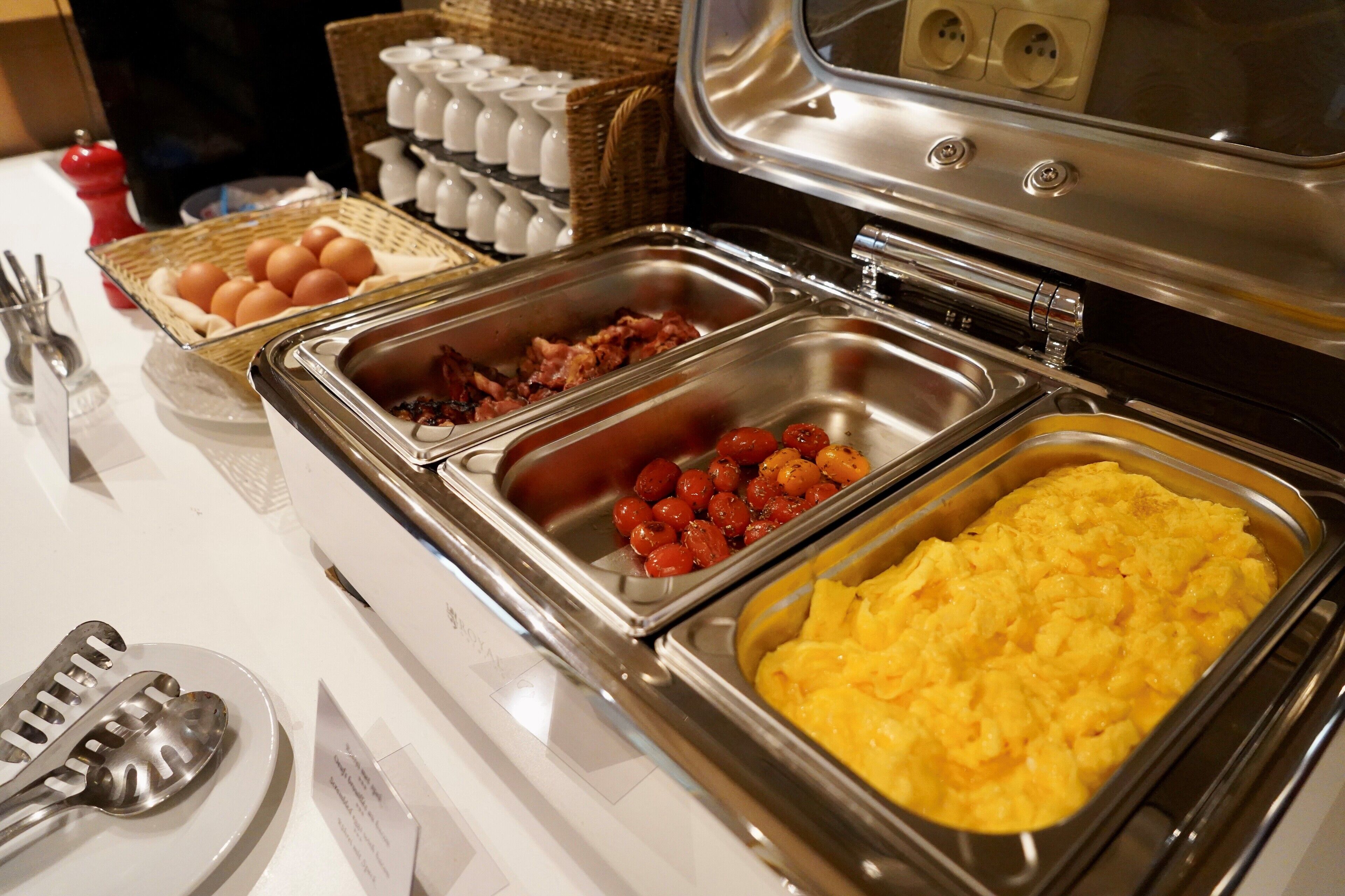 Un buffet proposant une variété de plats, notamment des œufs, du bacon et des œufs brouillés.