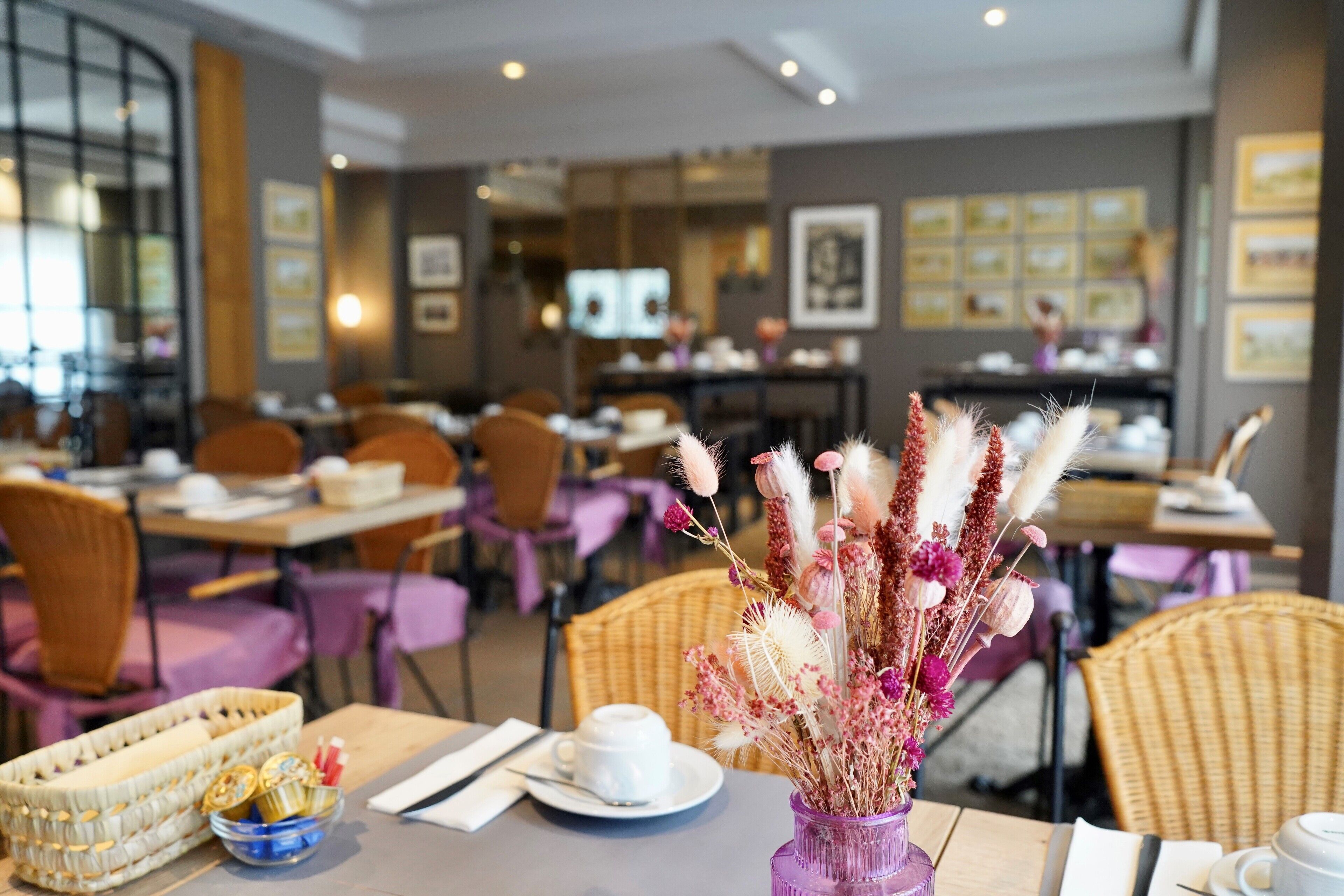 A restaurant interior with tables, chairs, and a vase of flowers.