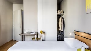 Ein Hotelzimmer mit Bett, Schreibtisch, Stuhl, Kleiderschrank und einem kleinen Tisch mit einer Tasse.