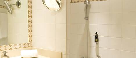 A bathroom with a sink, mirror, and shower.