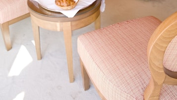 A hotel room with a bed, two chairs, a small table with breakfast items, and a mirror on the wall.
