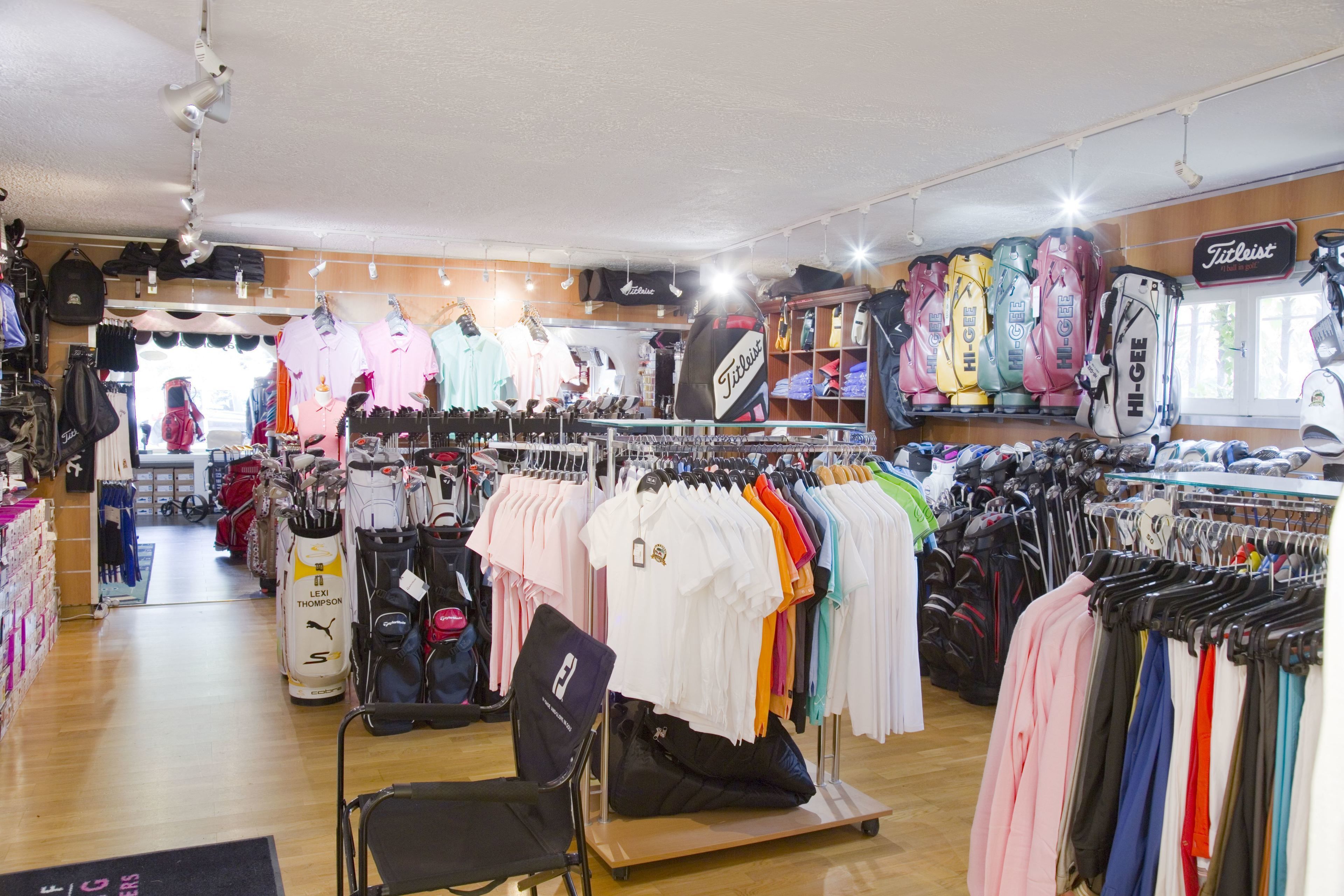 A clothing store with racks of shirts and a display of golf bags.