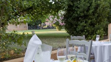 Un área de comedor al aire libre con manteles blancos, una botella de champán y una copa de vino blanco.