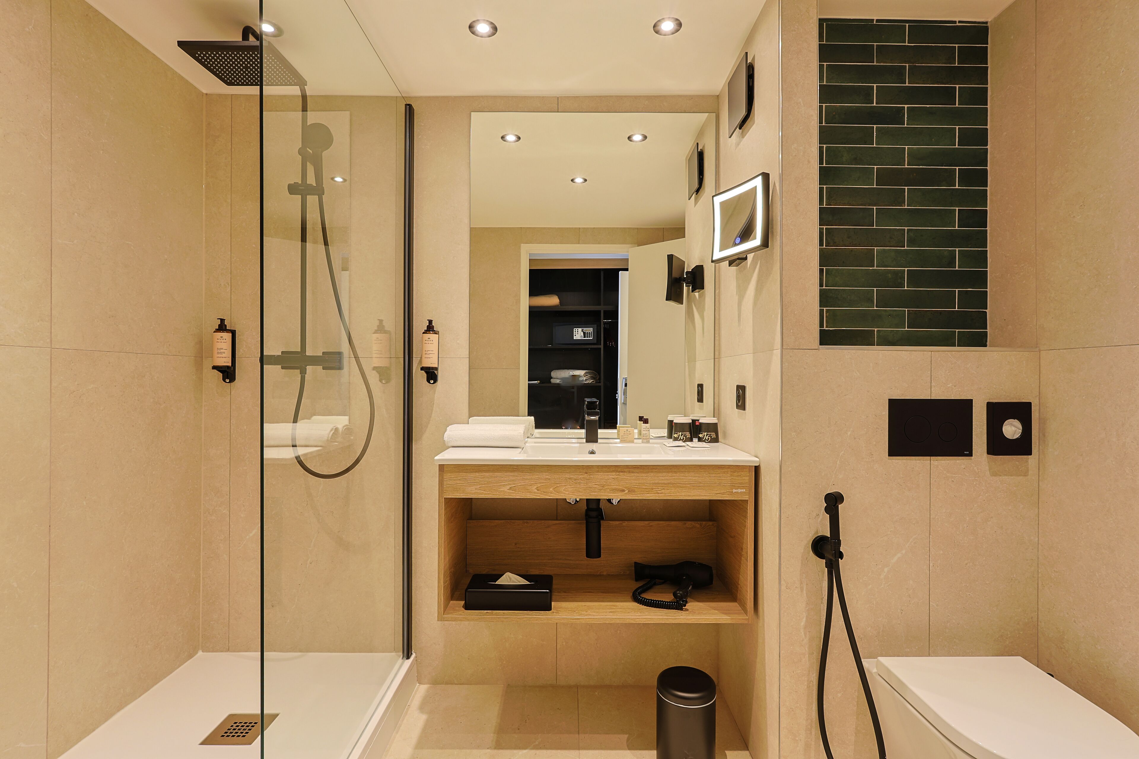 A modern bathroom with a glass-enclosed shower, a wooden vanity, and a black trash bin.