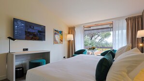 Een hotelkamer met een bed, bureau, televisie en raam met gordijnen.