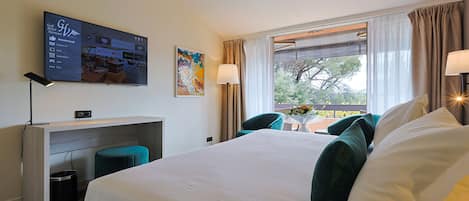 A hotel room with a bed, a desk, a TV, and a window with curtains.