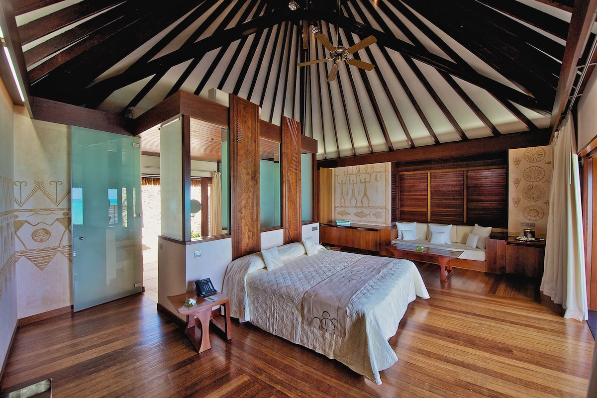 Um quarto espaçoso com uma cama grande, um banco de madeira e uma escrivaninha.