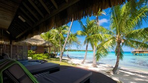 A beachside resort with a wooden deck, lounge chairs, a thatched-roof structure, and palm trees. - Hotel Kia Ora Resort & Spa (Rangiroa)
