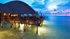 An overwater bungalows with thatched roofs, wooden deck, and clear blue water. - Hotel Kia Ora Resort & Spa (Rangiroa)