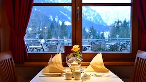 A table set for two with a mountain view, a vase with a yellow flower, and a name card. - IFA Alpenhof Wildental Hotel Kleinwalsertal (Mittelberg)