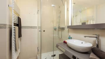A modern bathroom with a glass-enclosed shower, a white sink, and a towel rack.