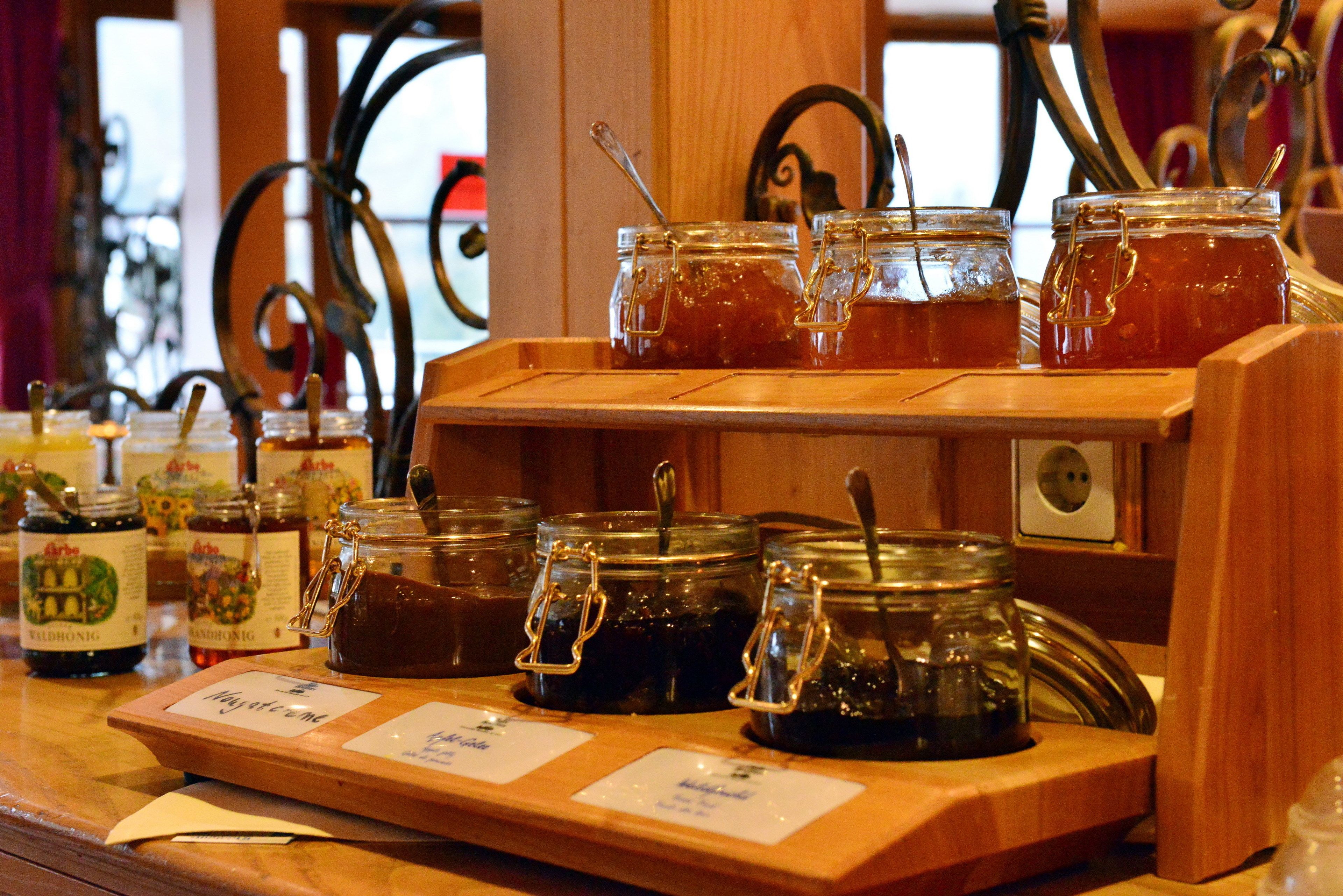 A wooden display with multiple glass jars of honey, each labeled with its name.