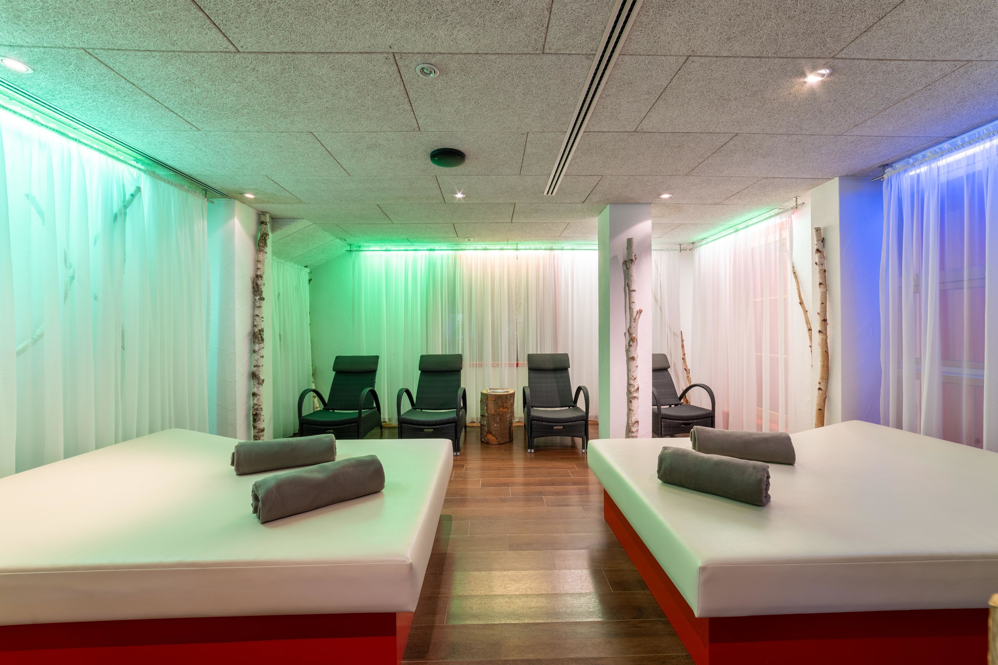 A room with two beds, a small table, and three chairs.