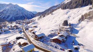 Un village de montagne enneigé, avec ses maisons traditionnelles en bois, une voie ferrée et une vue dégagée sur les montagnes environnantes.