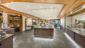 Un vaste espace buffet doté de plusieurs points de service, d’un îlot central et d’un plafond en bois agrémenté d’un éclairage encastré.