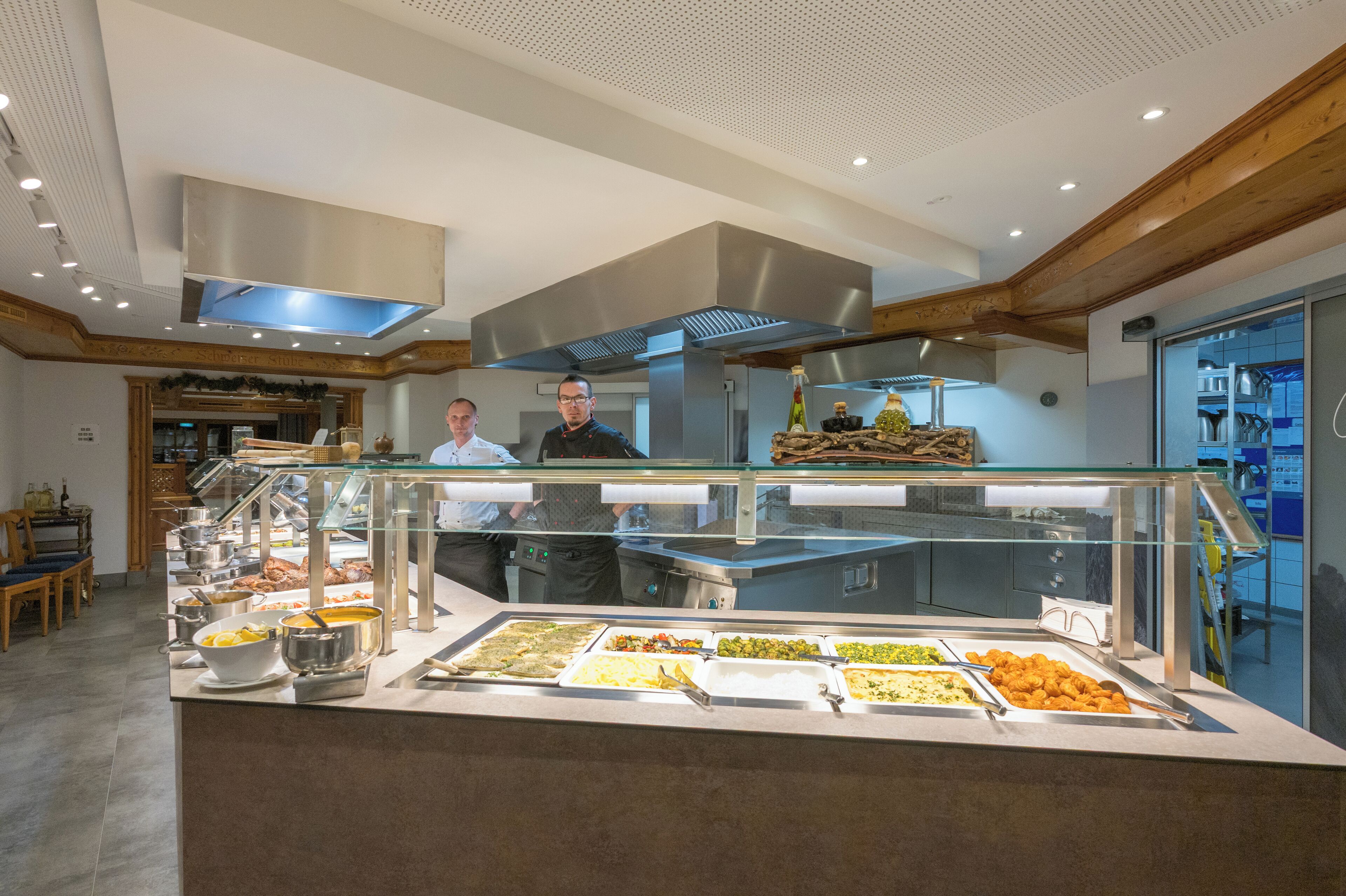 A buffet area with various food options and a kitchen in the background.