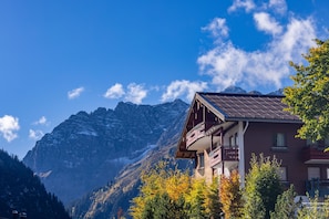 A mountain lodge with a balcony, surrounded by trees and mountains.
