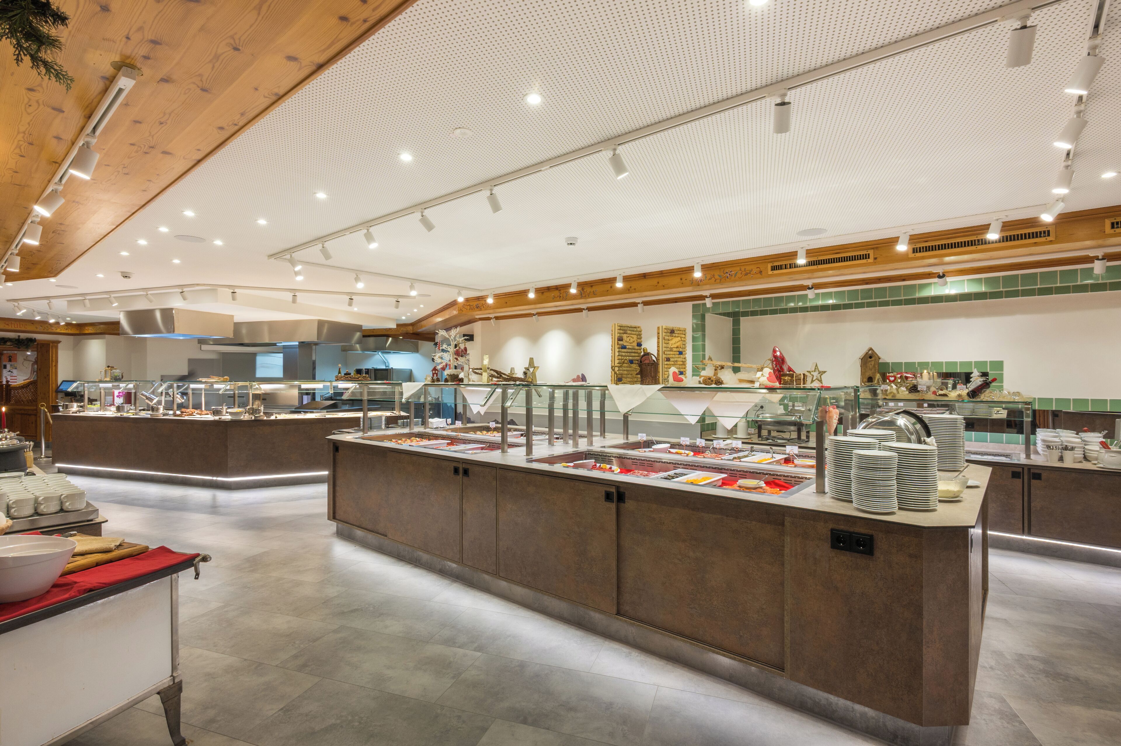 A buffet area with multiple food stations, a central serving counter, and a modern kitchen in the background.