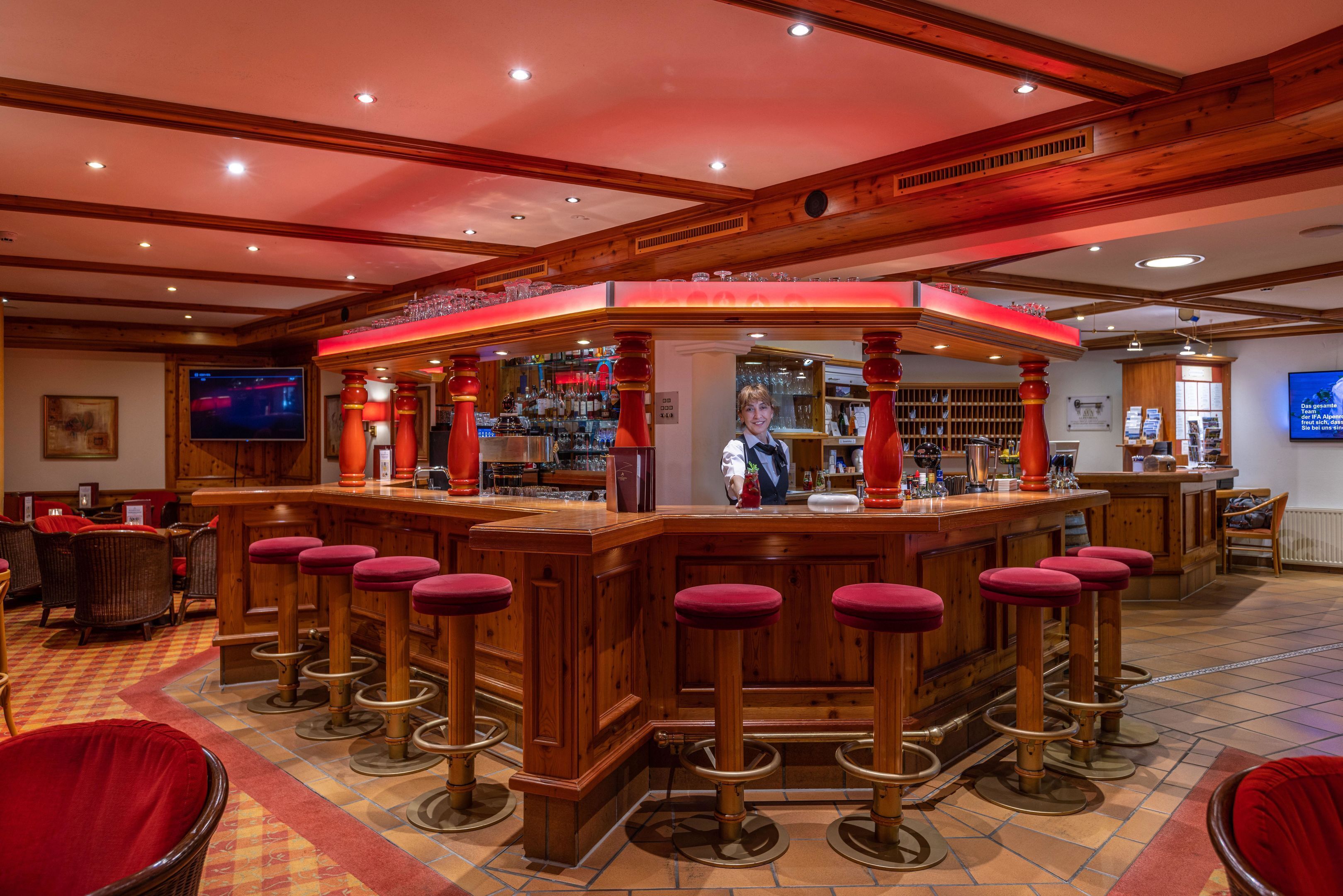 Een bar met houten barkrukken, een televisie en een toonbank vol flessen.