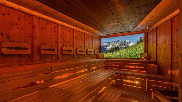 Un sauna avec des bancs en bois et une vue sur un paysage montagneux.