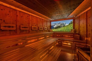 Een sauna met houten banken en uitzicht op een berglandschap.