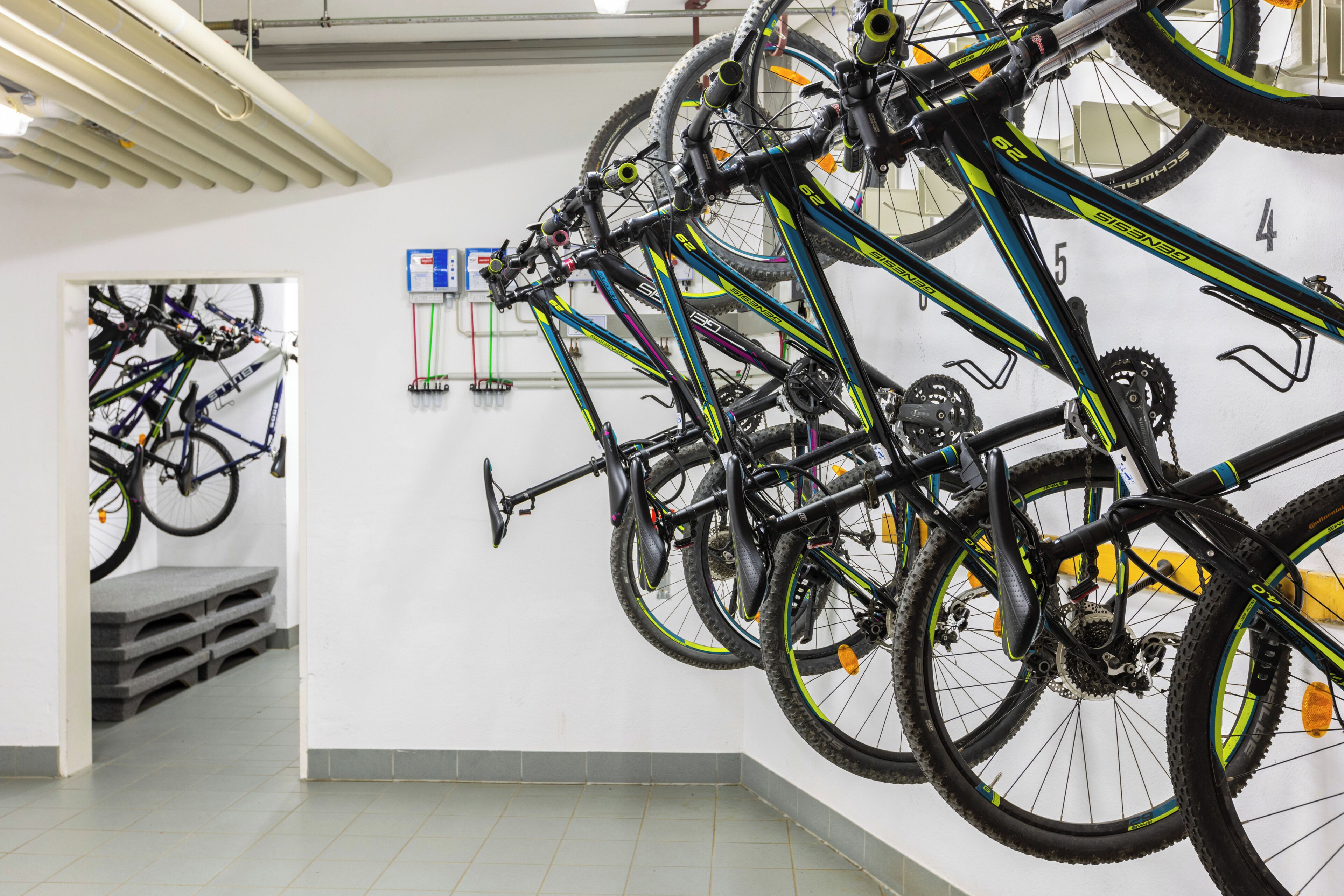 Ein Fahrradabstellbereich mit mehreren Fahrrädern, einem an der Wand befestigten Schild und einer Tür zu einem anderen Raum.