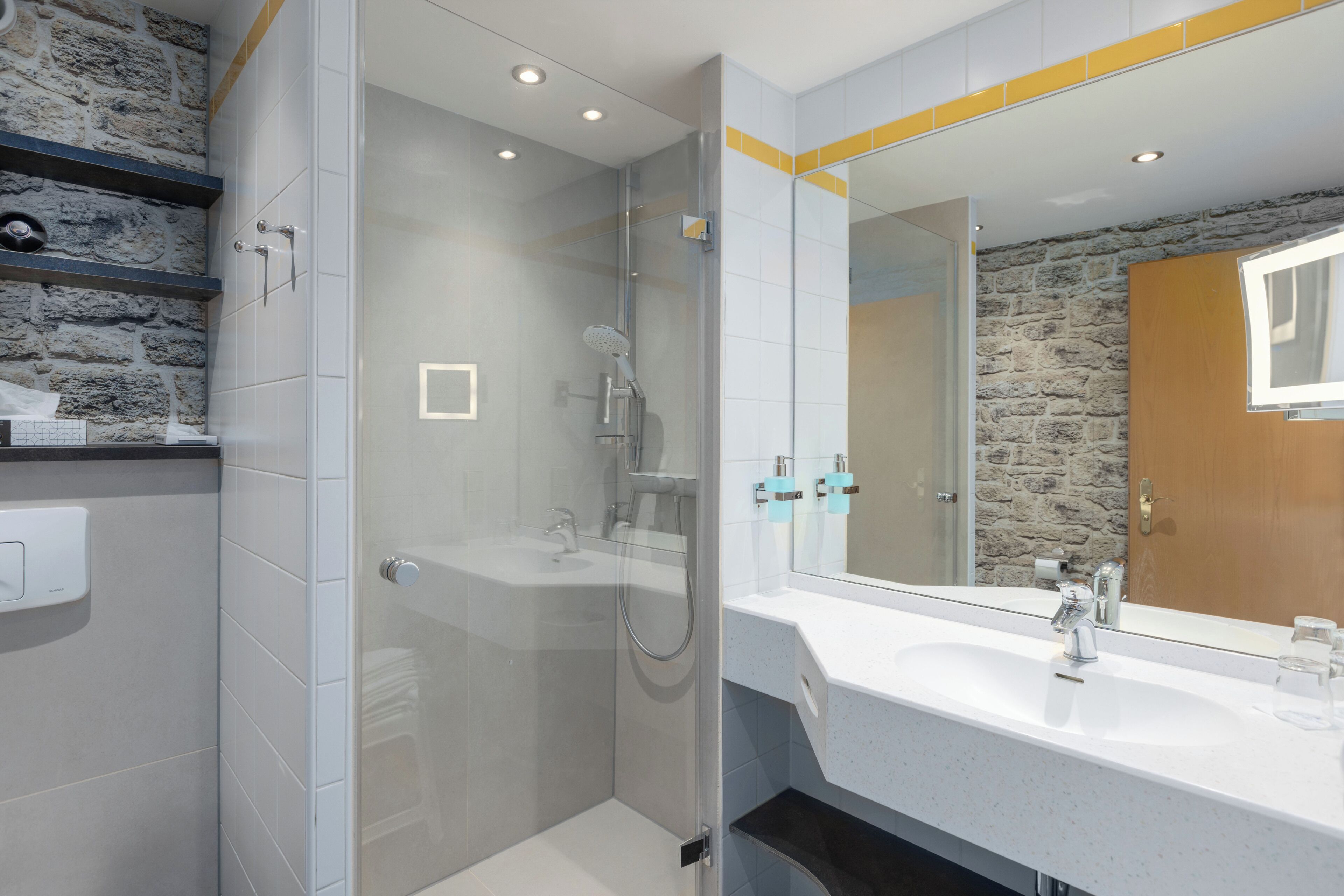 Un baño moderno con ducha envuelta en vidrio, un lavabo blanco y un espejo grande.